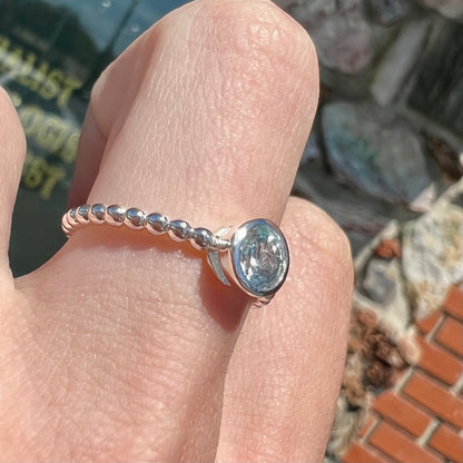 A silver, bezel set, round cut sky blue topaz solitaire ring.  The band is made of connected silver balls.