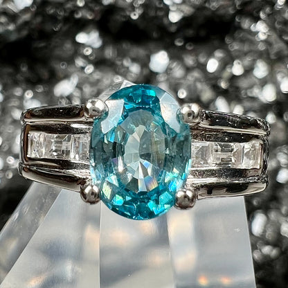 A sterling silver ring set with an oval cut blue zircon center stone and channel set white zircon accents.