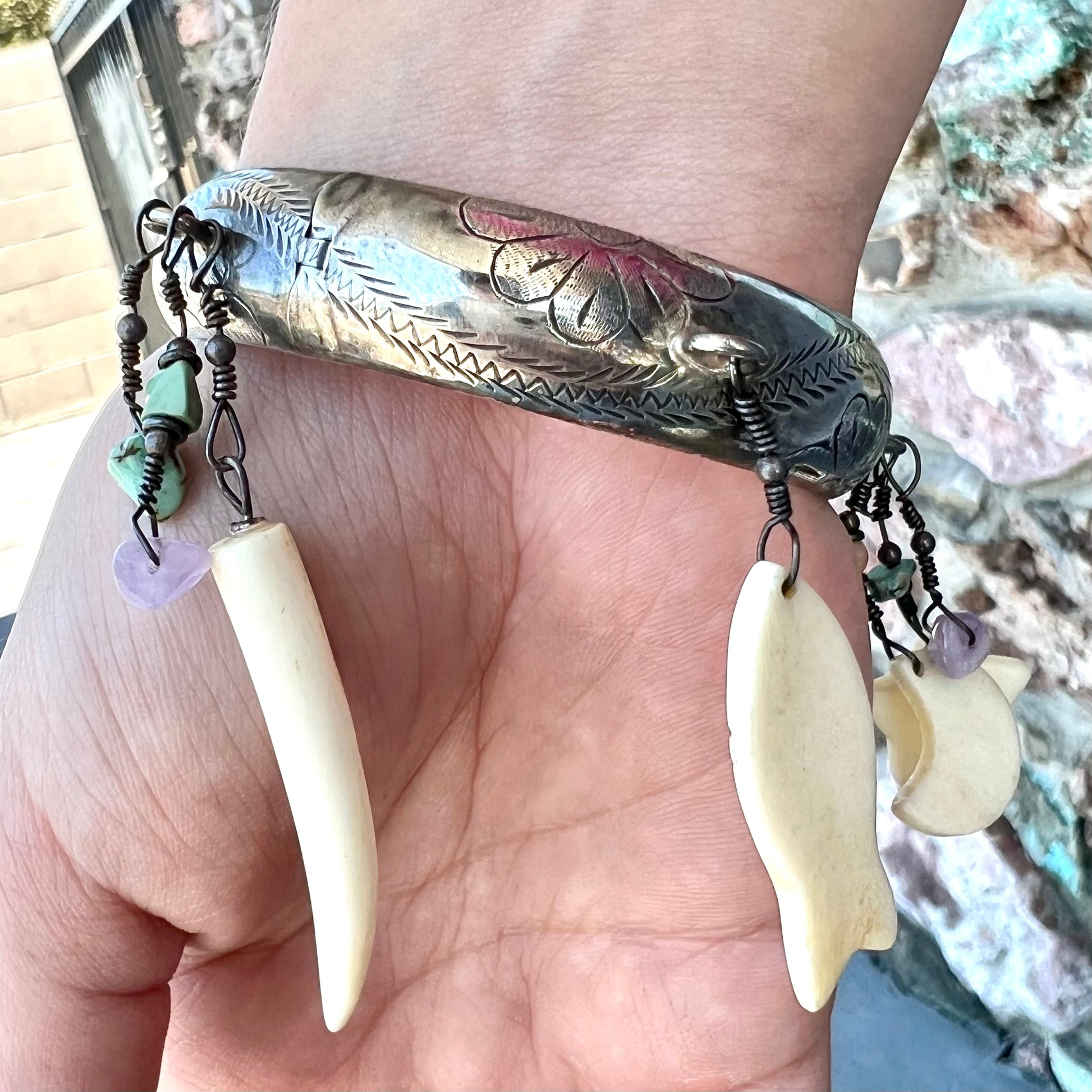 A Native American sterling silver bangle bracelets attached with carved bone, gemstone, and silver charm fetishes.