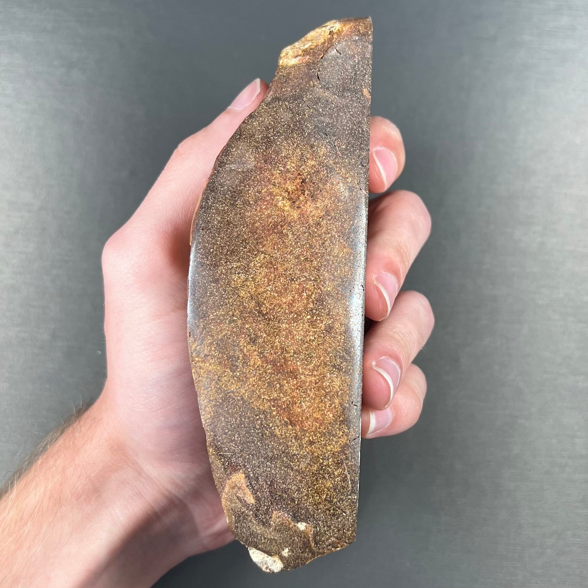 A polished Quilpie boulder opal specimen.  The stone has a stripe of bright blue, green, and purple.
