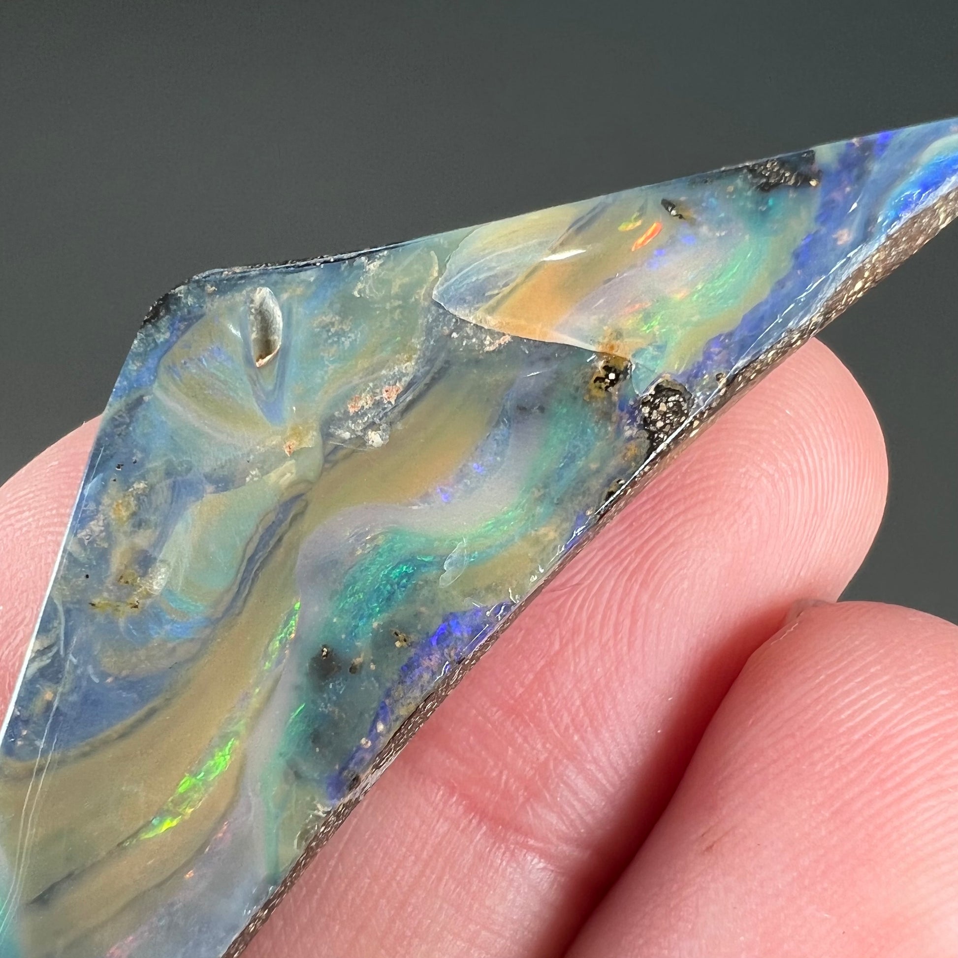 A loose, triangular shaped boulder opal stone from Queensland, Australia.