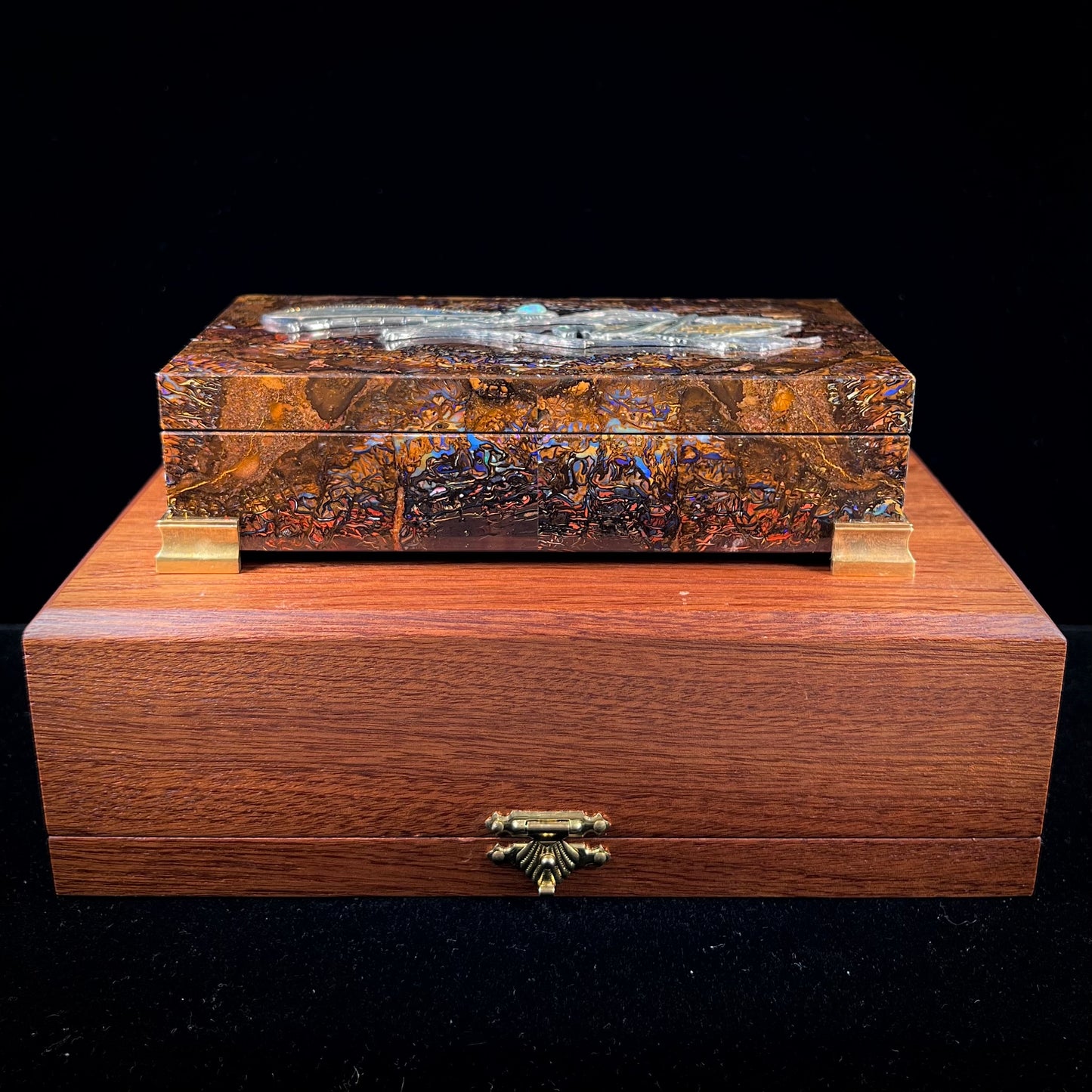 A stone box made from Koroit, Australian boulder opal featuring the motif of a dragonfly and cricket made from sterling silver, set with yellow diamonds, an emerald, and a crystal opal.