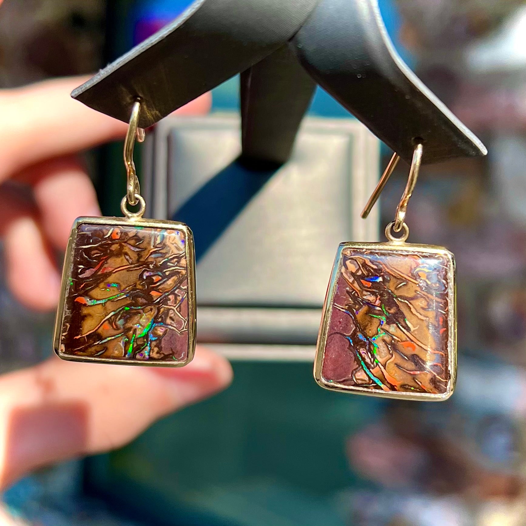 A pair of yellow gold French wire dangle earrings set with Koroit boulder opal.