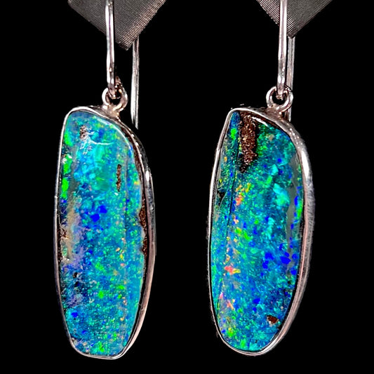 A pair of white gold boulder opal French wire dangle earrings.  The opal is predominantly glimmery blue.