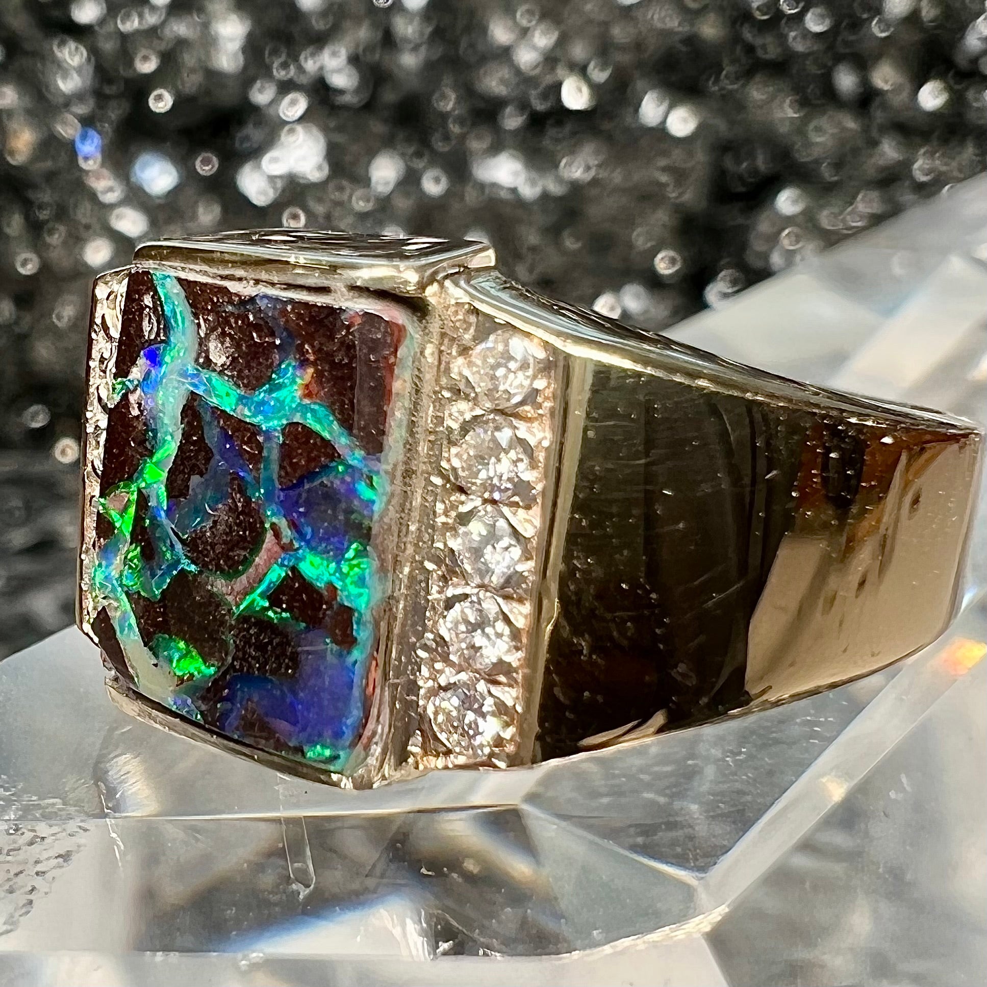 A men's gold boulder opal and diamond ring.  The opal shows blue and green colors.
