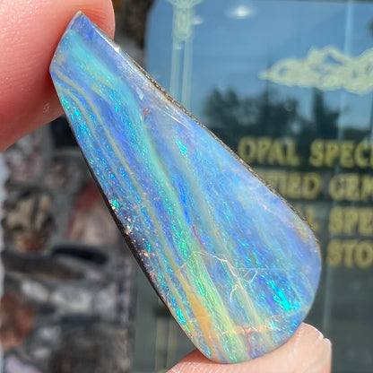 A loose, polished, freeform drop shaped boulder opal stone from Quilpie, Australia.