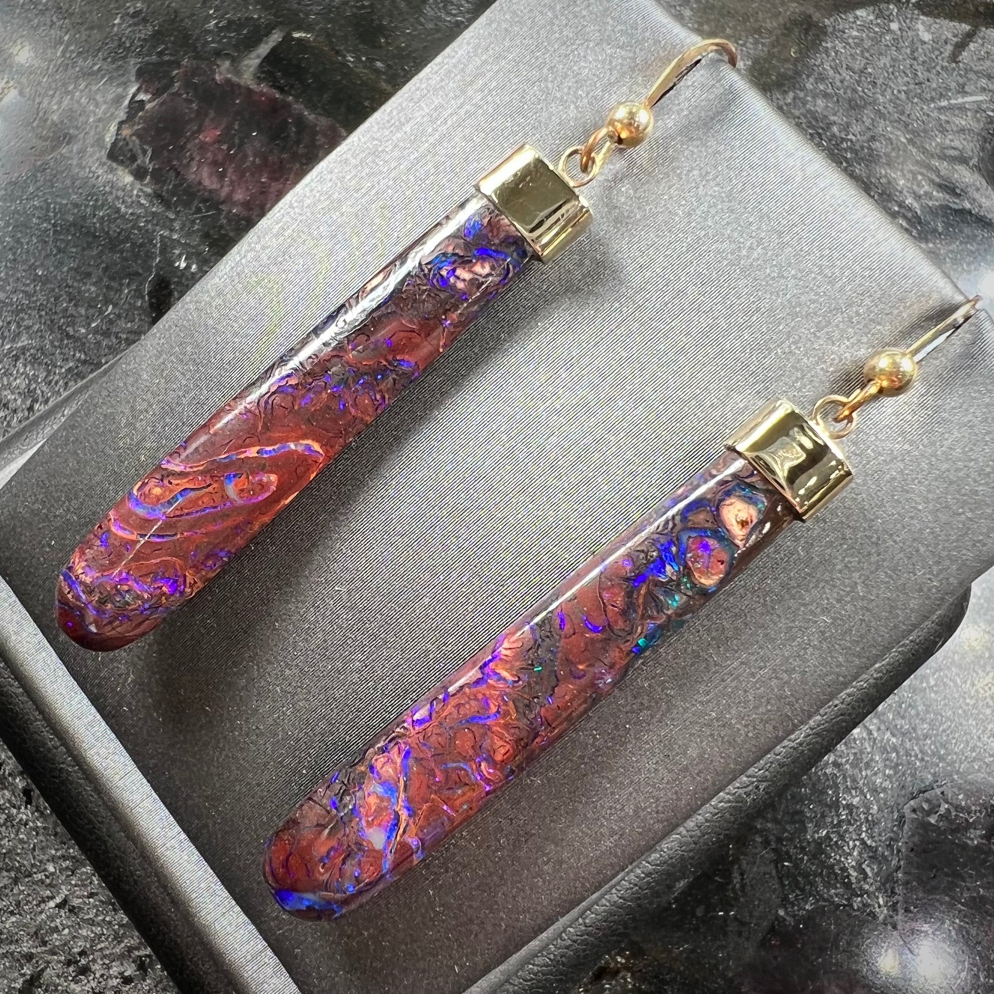A pair of yellow gold cap Koroit boulder opal dangle earrings.  Purple highlights are seen.