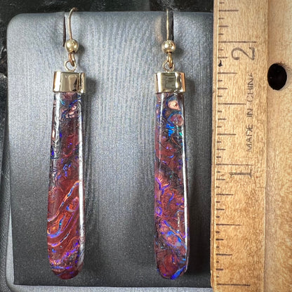 A pair of yellow gold cap Koroit boulder opal dangle earrings.  Purple highlights are seen.