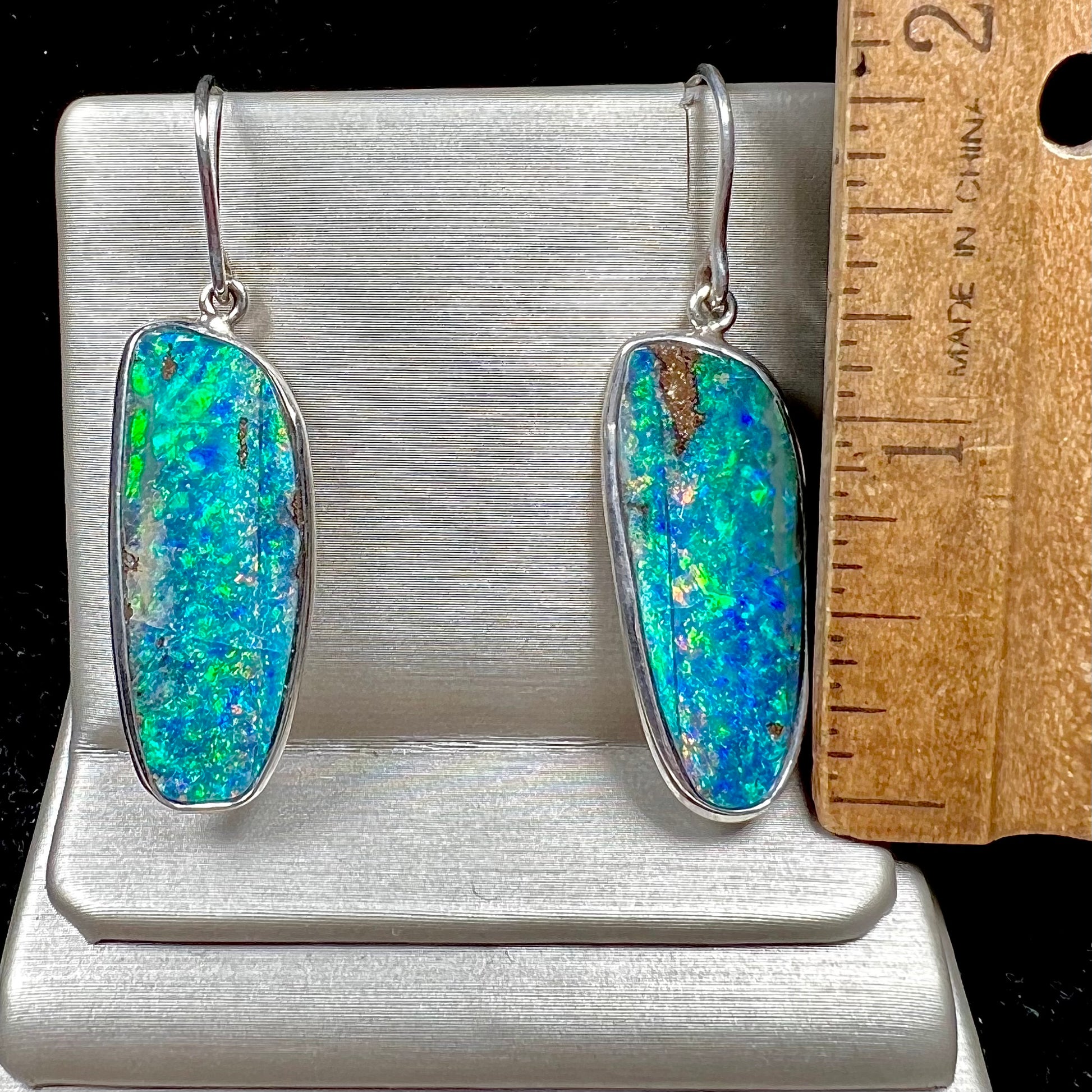 A pair of white gold boulder opal French wire dangle earrings.  The opal is predominantly glimmery blue.