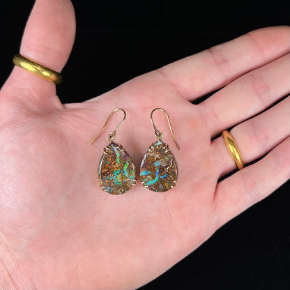A pair of ladies' yellow gold dangle earrings set with pear shaped natural boulder opal stones from Koroit, Australia.