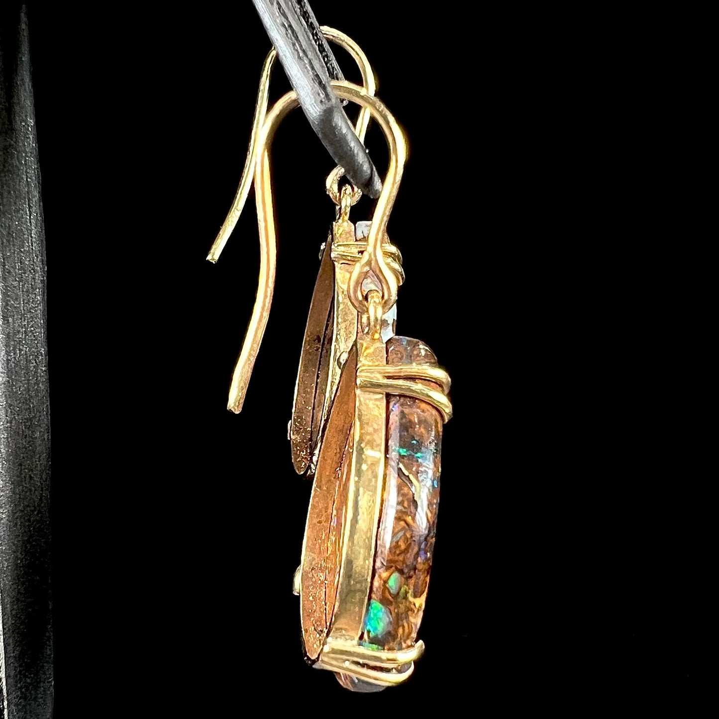 A pair of ladies' yellow gold dangle earrings set with pear shaped natural boulder opal stones from Koroit, Australia.