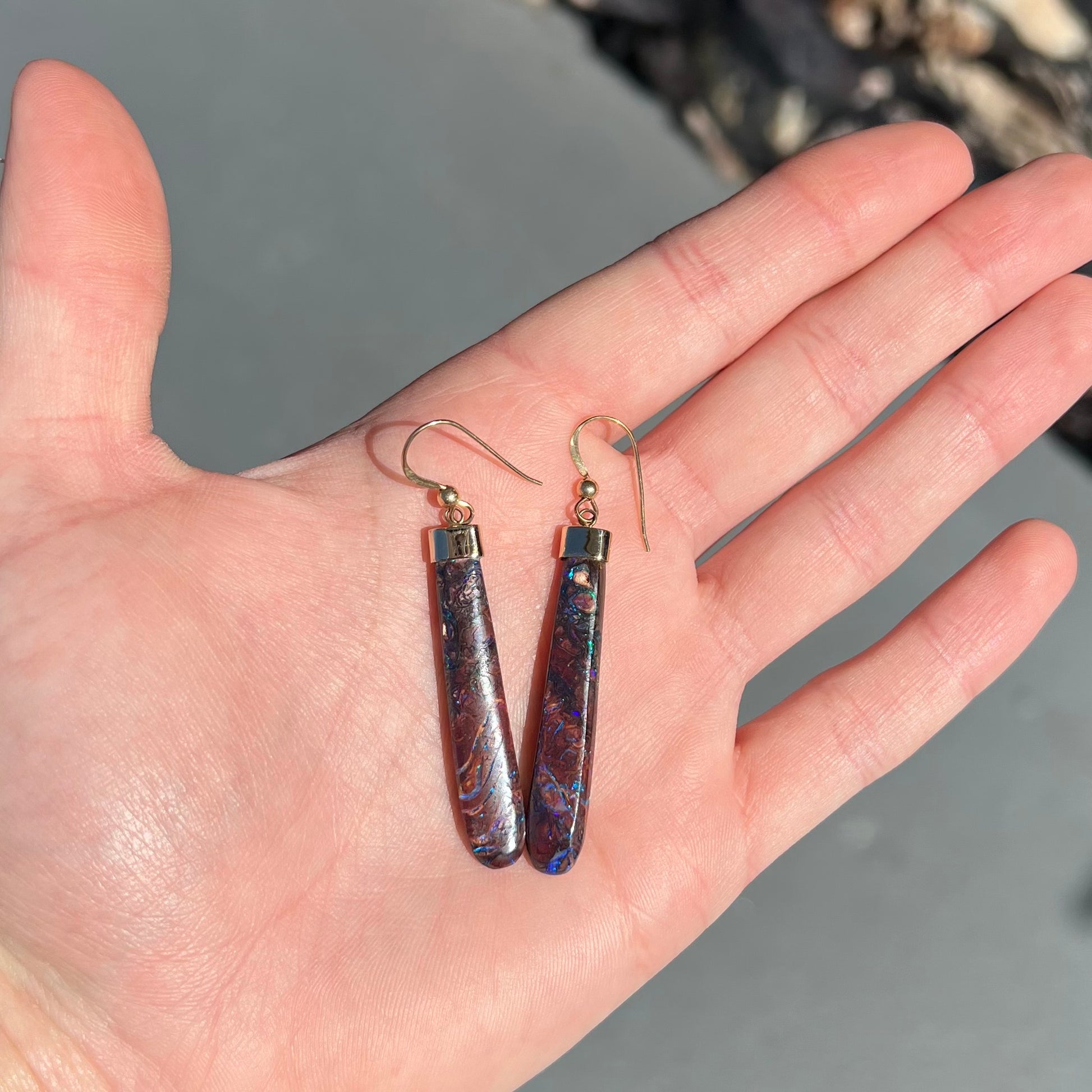 A pair of yellow gold cap Koroit boulder opal dangle earrings.  Purple highlights are seen.