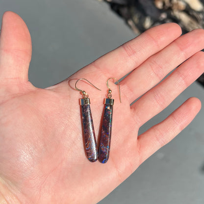 A pair of yellow gold cap Koroit boulder opal dangle earrings.  Purple highlights are seen.