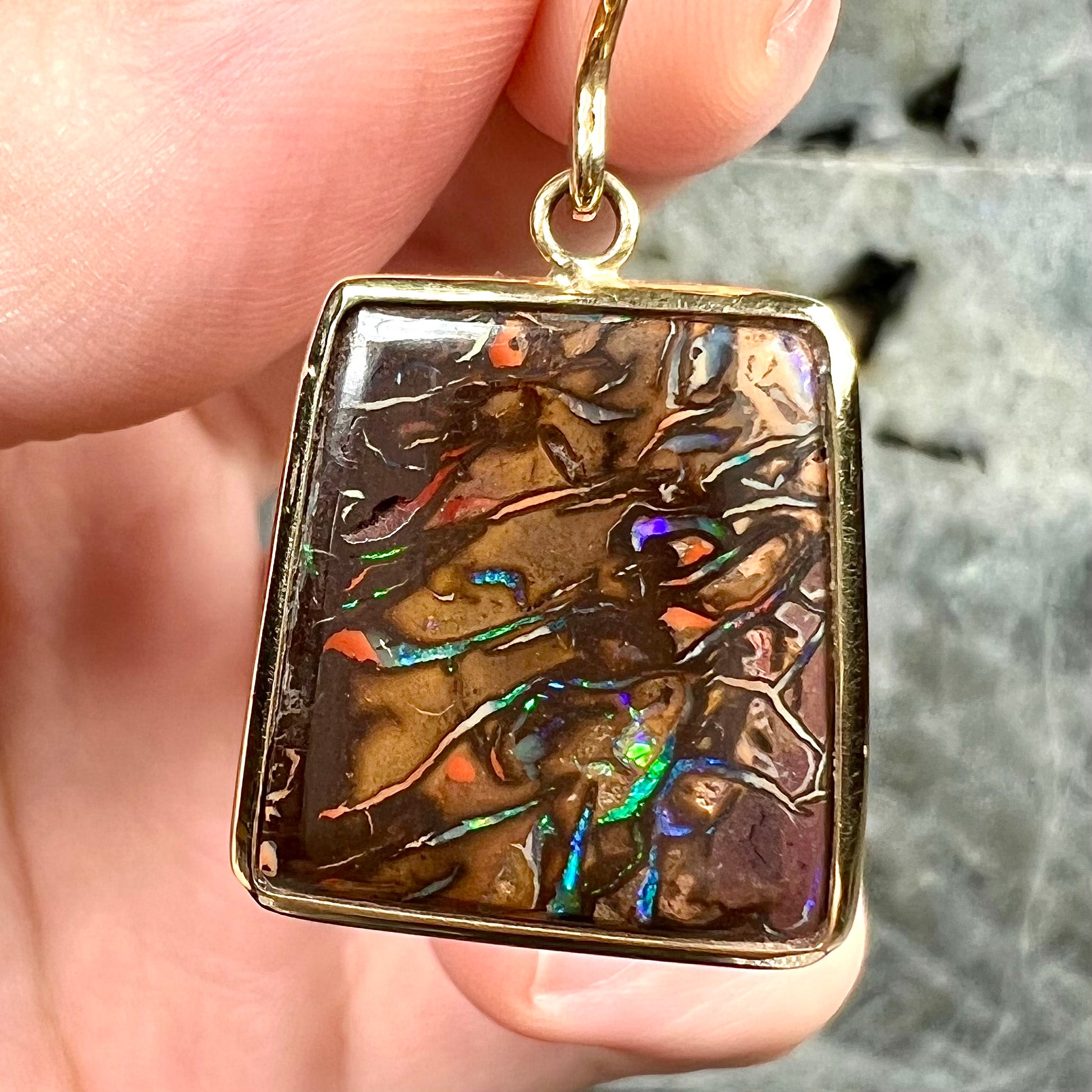 A pair of yellow gold French wire dangle earrings set with Koroit boulder opal.
