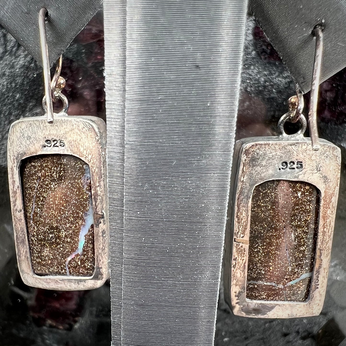 A pair of handmade sterling silver boulder opal earrings.  The earrings dangle from French wire hooks.