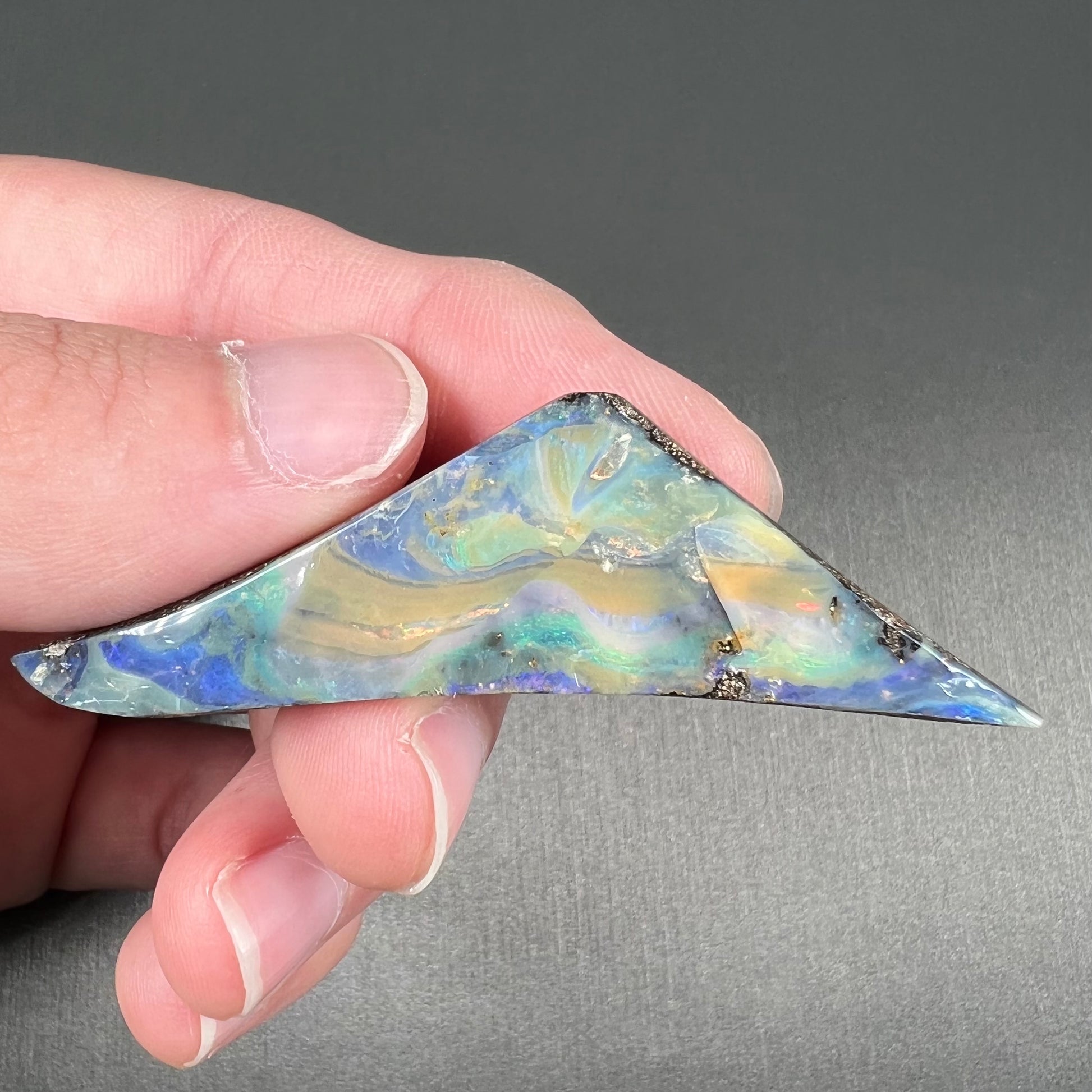 A loose, triangular shaped boulder opal stone from Queensland, Australia.