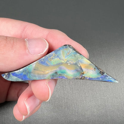 A loose, triangular shaped boulder opal stone from Queensland, Australia.