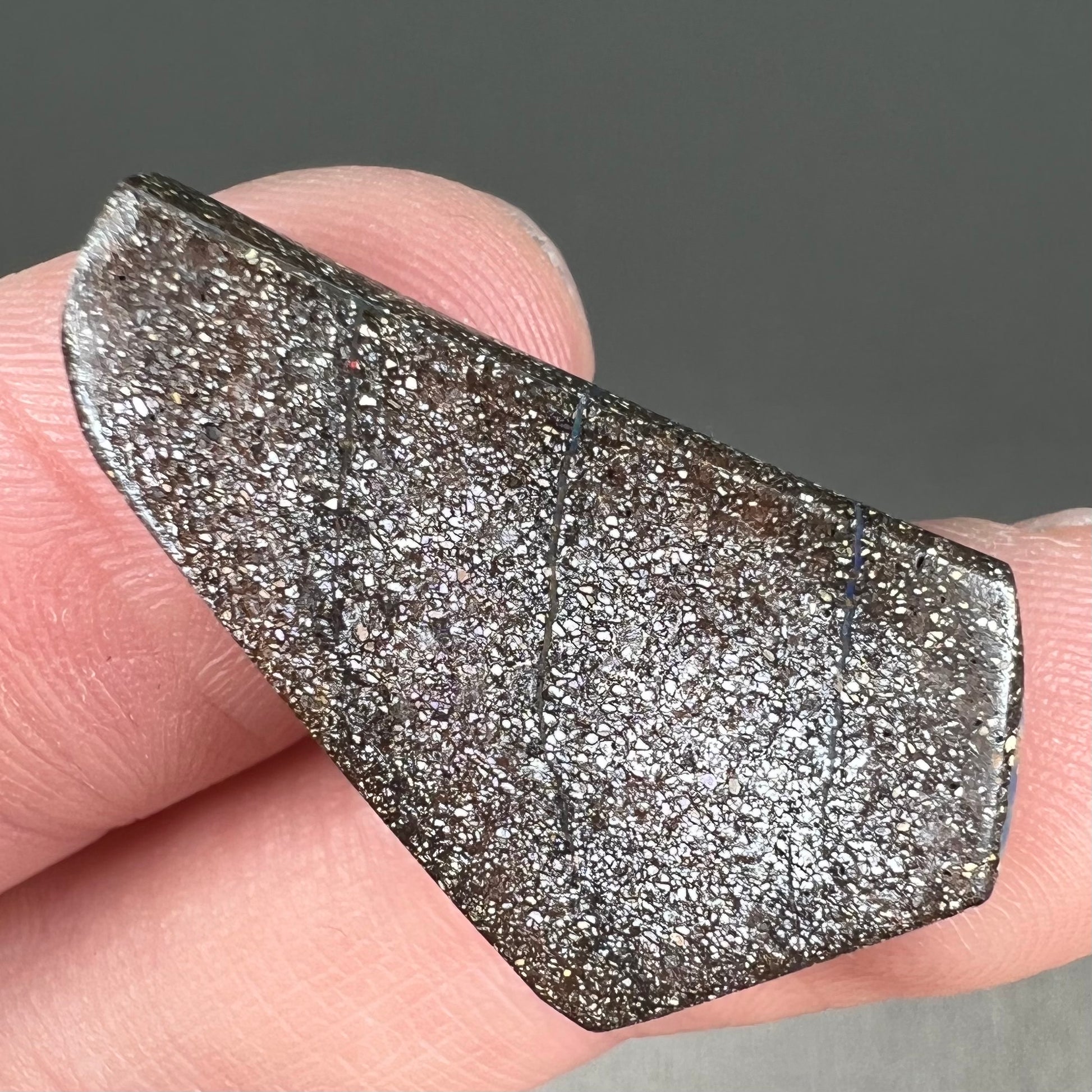 A loose, polished, freeform cut boulder opal stone from Queensland, Australia.