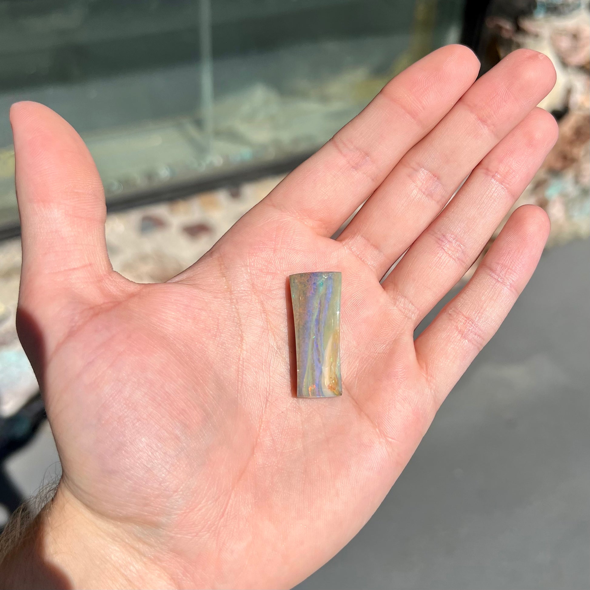 A polished, tapered rectangular cut boulder opal stone from Quilpie, Australia.
