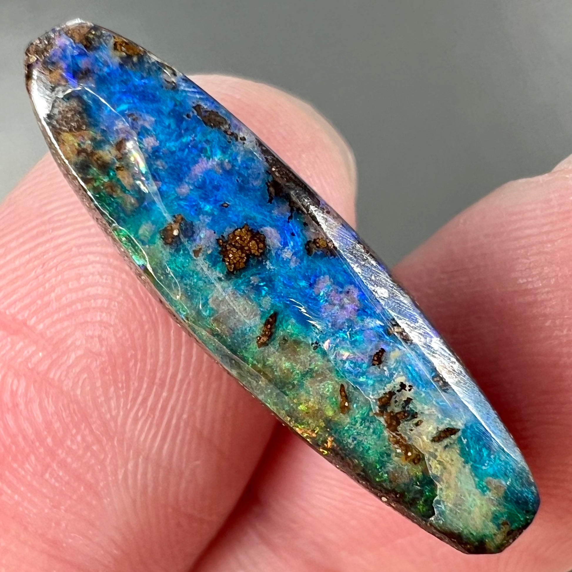 A loose, oval cabochon cut Australian boulder opal from Quilpie, Australia.  Predominant colors are blue and green.