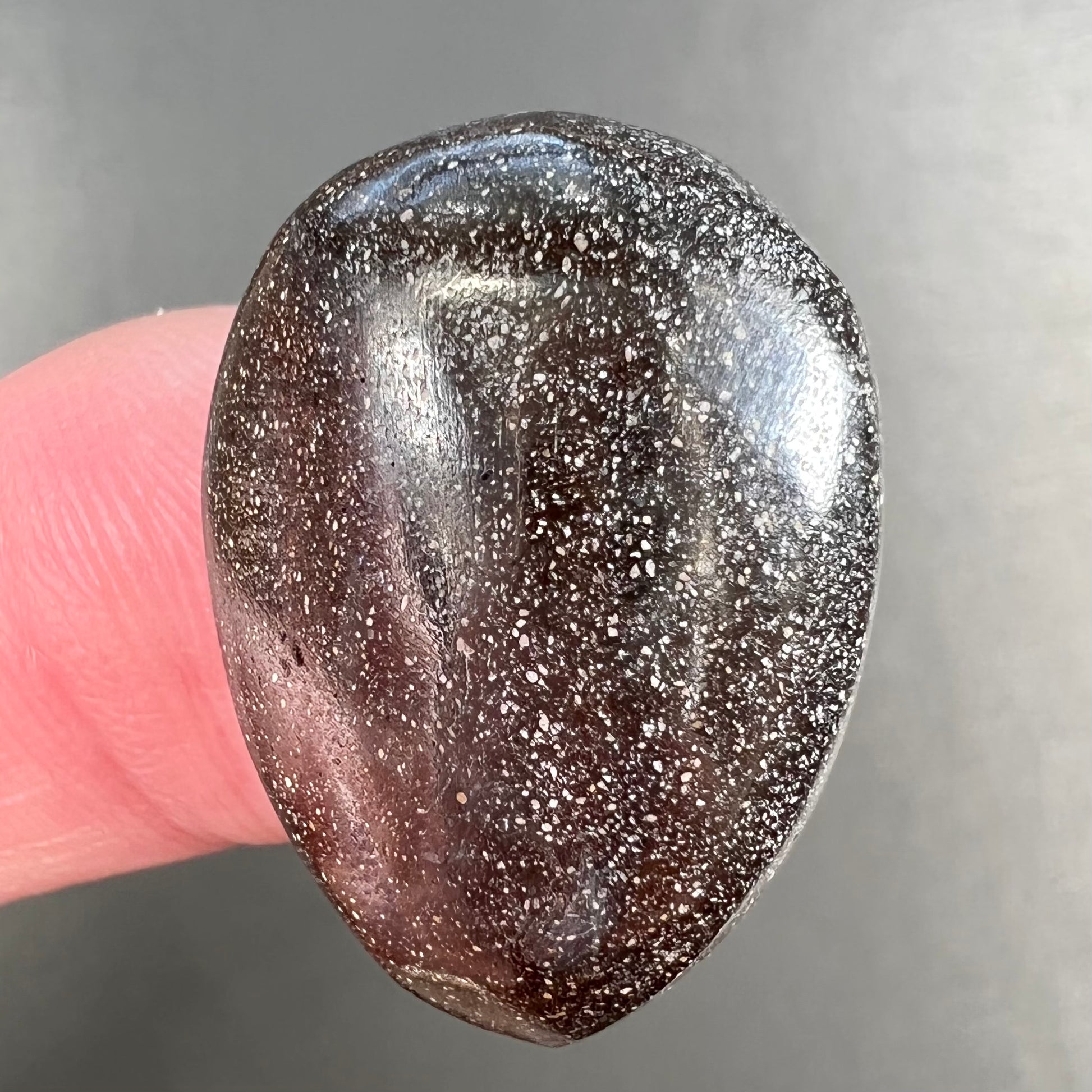 A loose, pear shaped Australian boulder opal.  The pattern on the opal resembles the face of a very sad man.