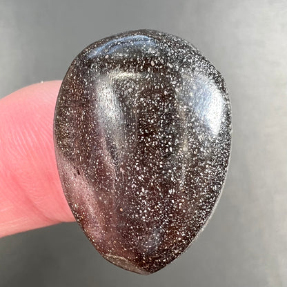 A loose, pear shaped Australian boulder opal.  The pattern on the opal resembles the face of a very sad man.