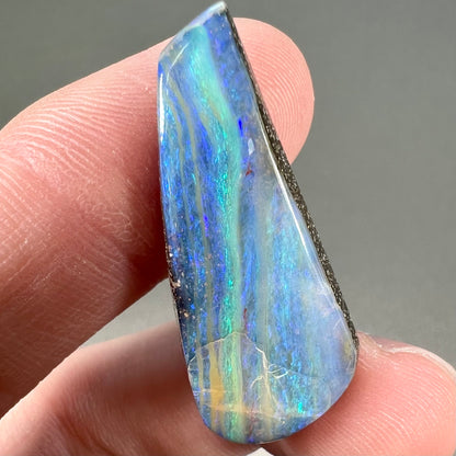 A loose, polished, freeform drop shaped boulder opal stone from Quilpie, Australia.