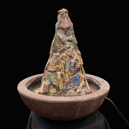 An indoor/outdoor three sided pyramid fountain made from Australian boulder opal, sitting in a bowl of Mexican fire opal.
