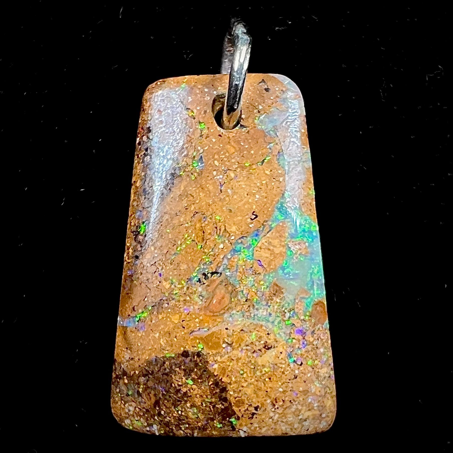 A drilled boulder opal stone with a sterling silver ring through the hole to be worn as a pendant.