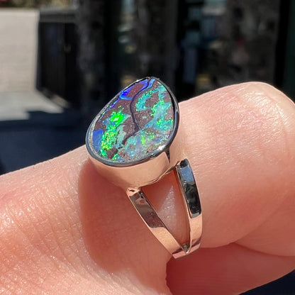 A split shank white gold boulder opal solitaire ring.  The stone has a natural hematite seam that runs through it.