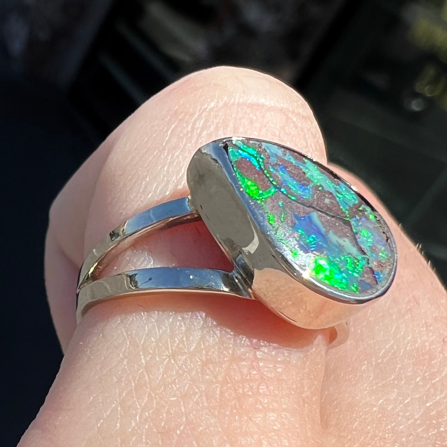 A split shank white gold boulder opal solitaire ring.  The stone has a natural hematite seam that runs through it.