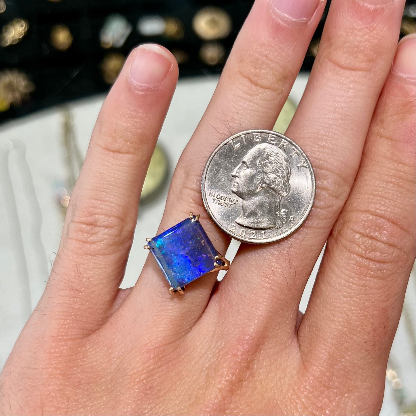 A ladies' boulder opal solitaire ring, handmade in yellow gold.  The stone is purple with flashes of blue, aqua, and green.