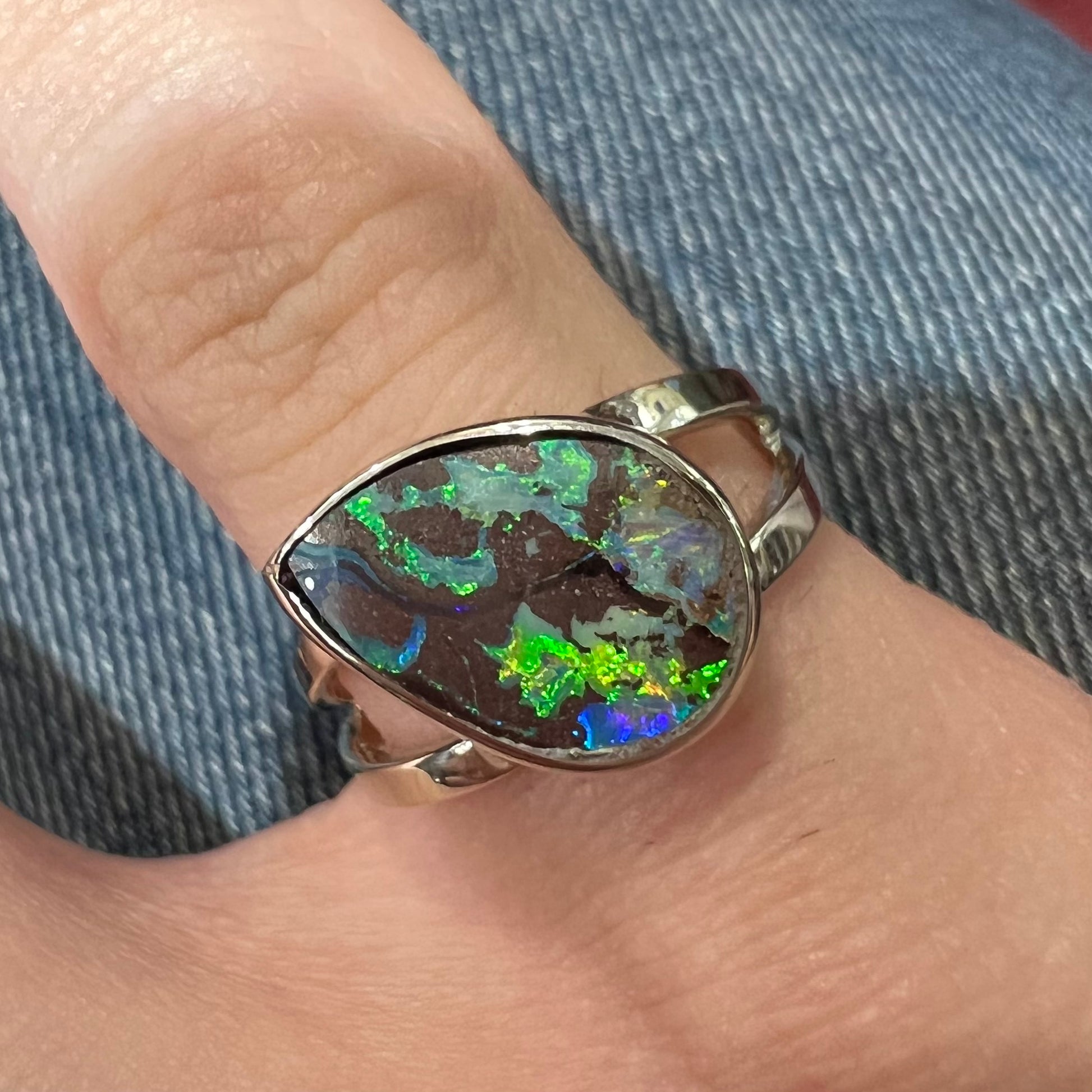 A split shank white gold boulder opal solitaire ring.  The stone has a natural hematite seam that runs through it.