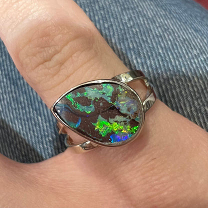 A split shank white gold boulder opal solitaire ring.  The stone has a natural hematite seam that runs through it.