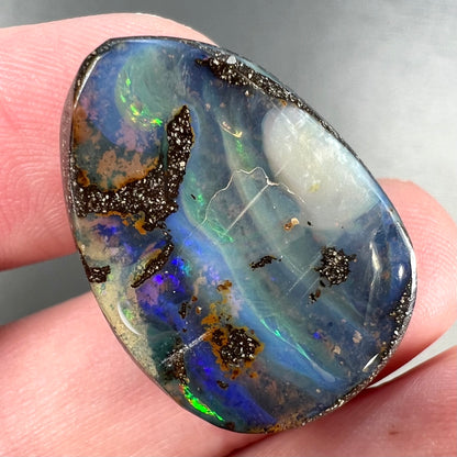 A loose, pear shaped Australian boulder opal.  The pattern on the opal resembles the face of a very sad man.