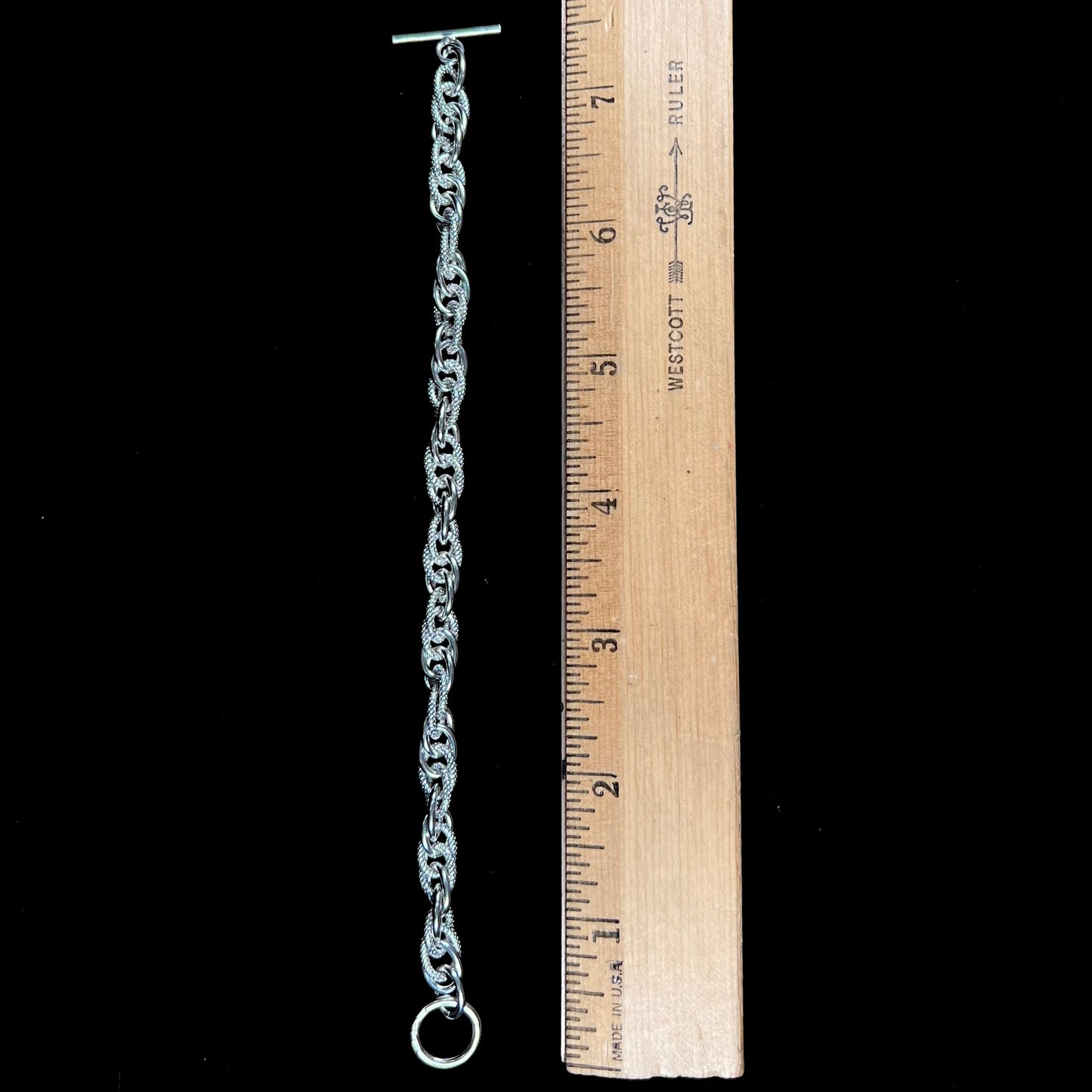 A silver toggle clasp link bracelet.  Some of the links are textured, and others are polished.  The toggle ring is stamped "India."