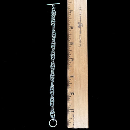 A silver toggle clasp link bracelet.  Some of the links are textured, and others are polished.  The toggle ring is stamped "India."