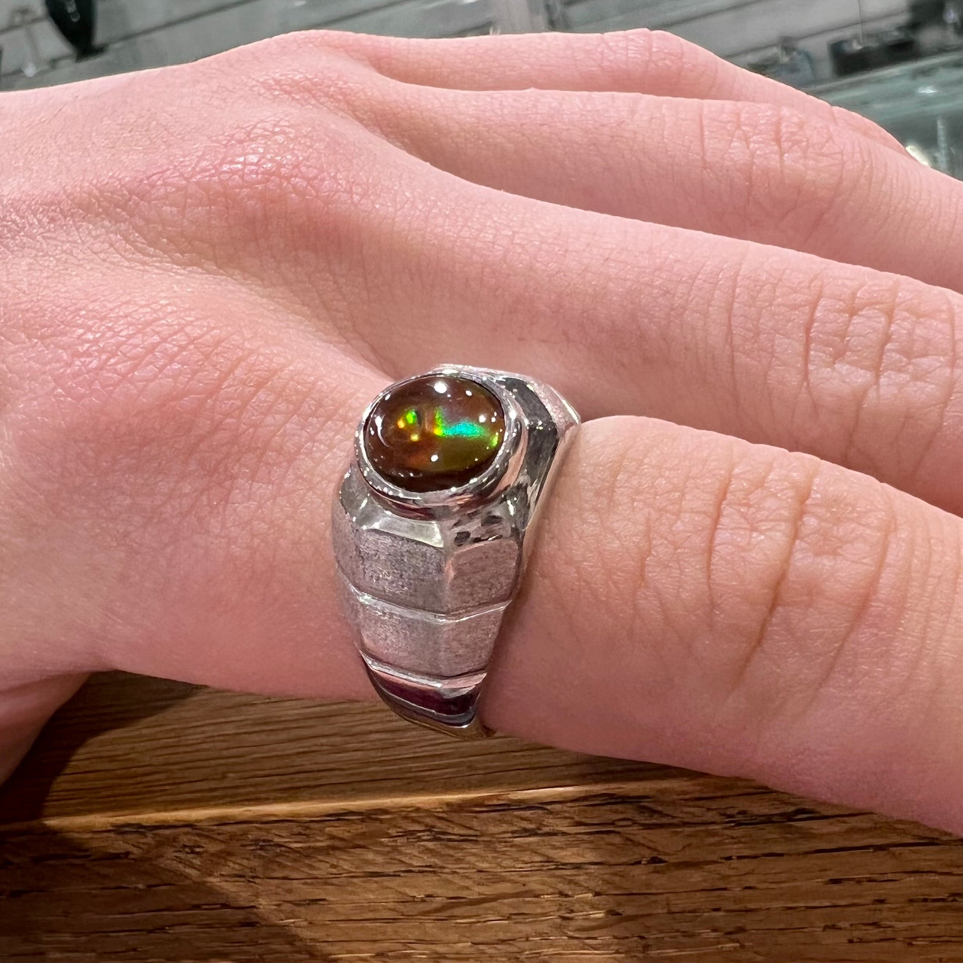A round cabochon cut red and green fire agate set in a brushed metal white gold men's ring.