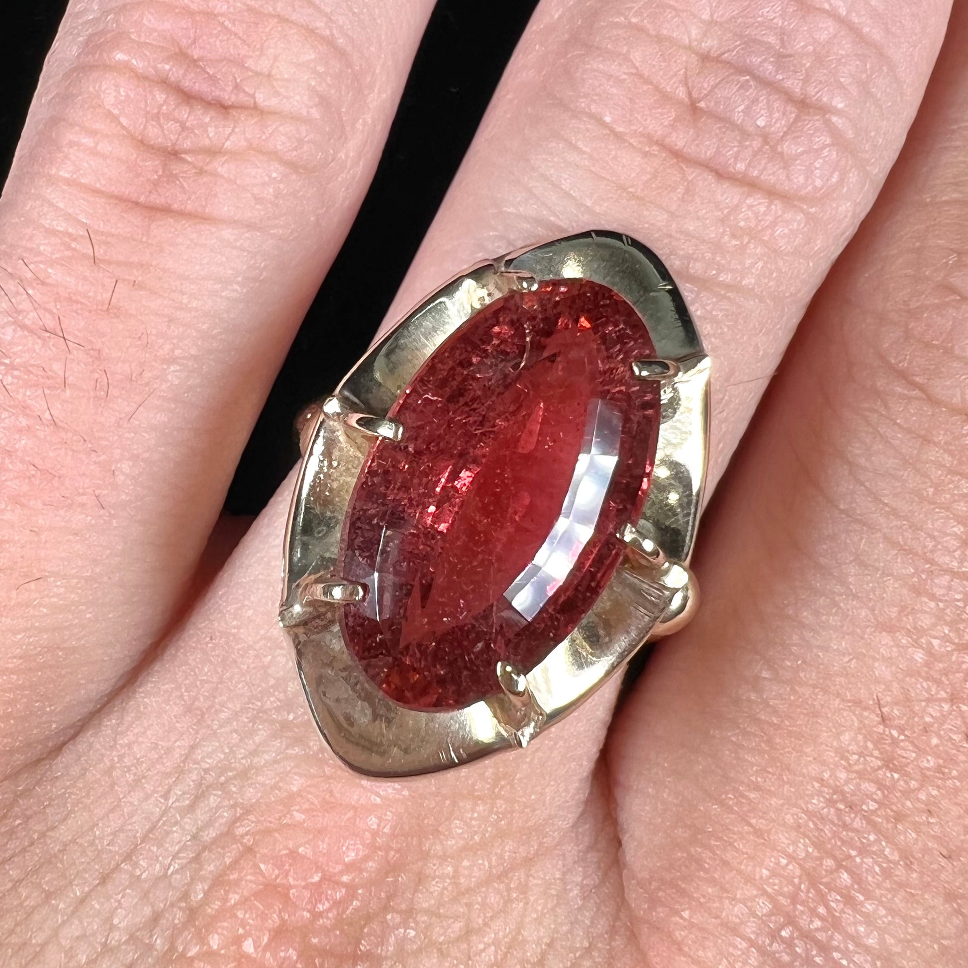 A yellow gold solitaire ring set with an oval cut, rootbeer colored tourmaline stone.