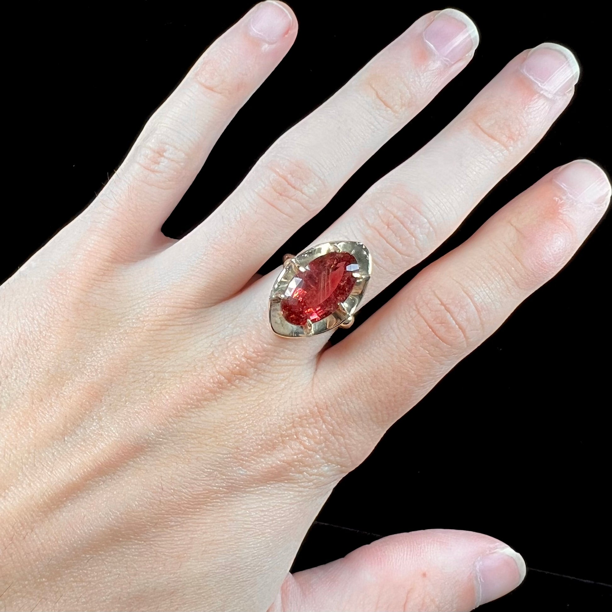 A yellow gold solitaire ring set with an oval cut, rootbeer colored tourmaline stone.