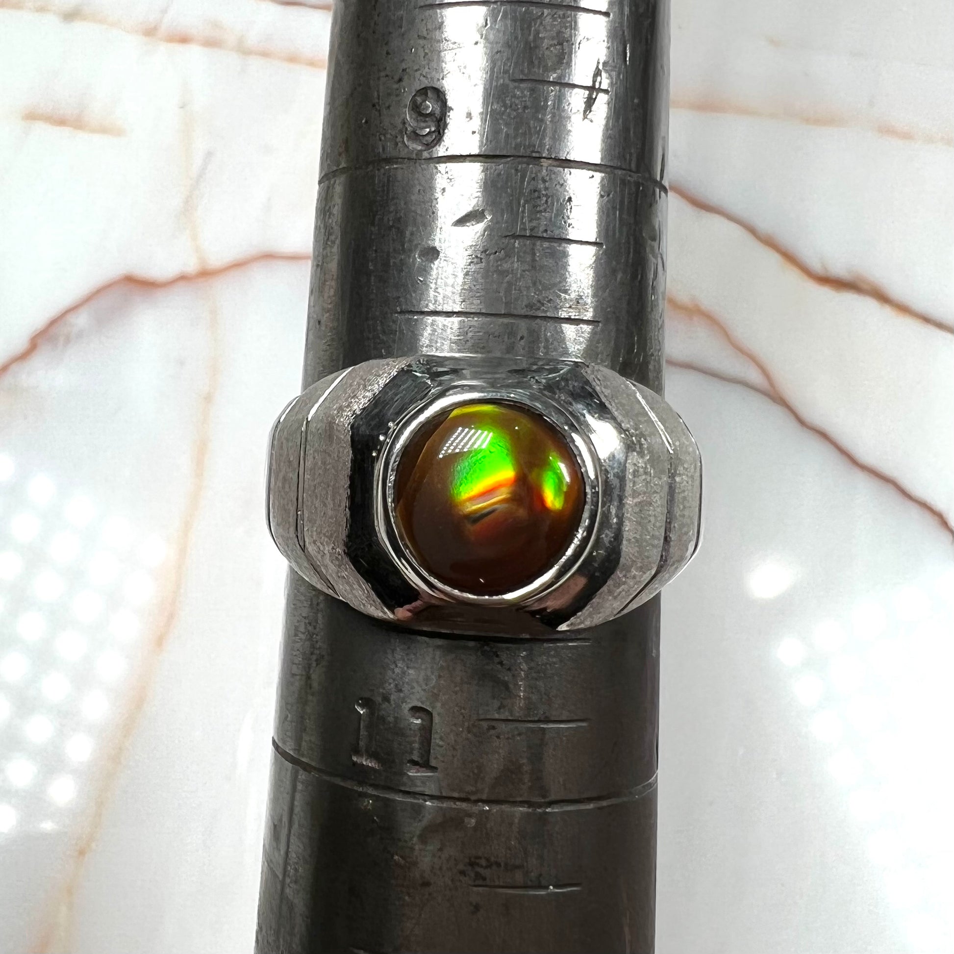 A round cabochon cut red and green fire agate set in a brushed metal white gold men's ring.