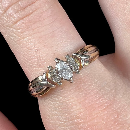 A ladies' two-tone white and yellow gold marquise cut diamond enagagement ring.  There are round diamond accents.