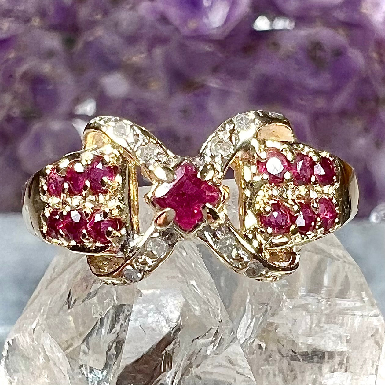 A yellow gold princess cut ruby ring set with round ruby and diamond accents.