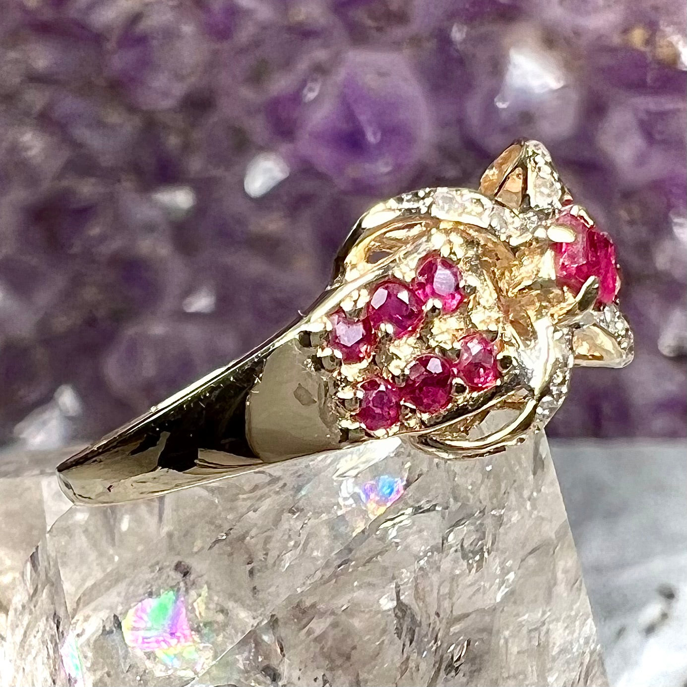 A yellow gold princess cut ruby ring set with round ruby and diamond accents.