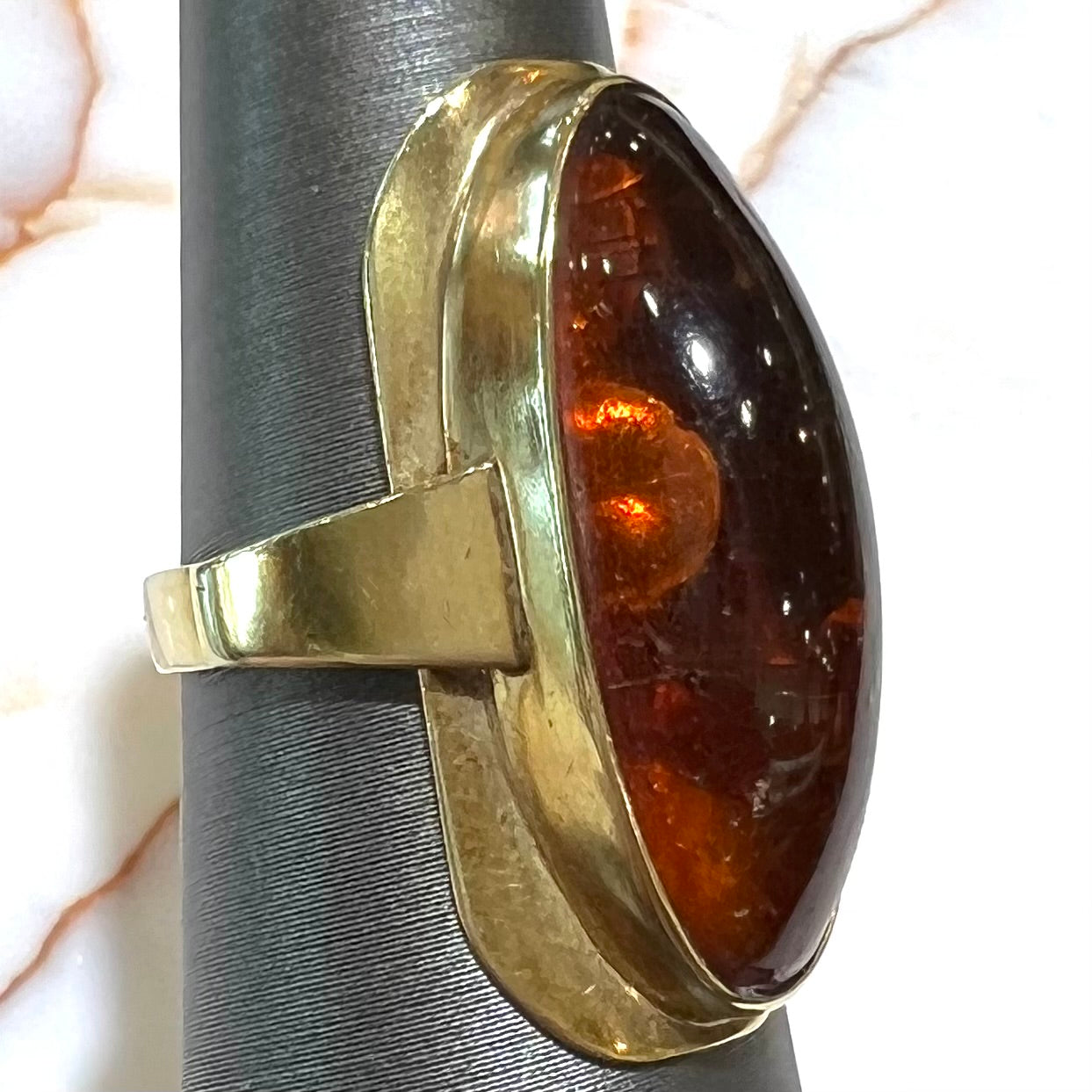 An oval cabochon cut Baltic amber stone set in a yellow gold ring and stamped "AMBER GUILD."