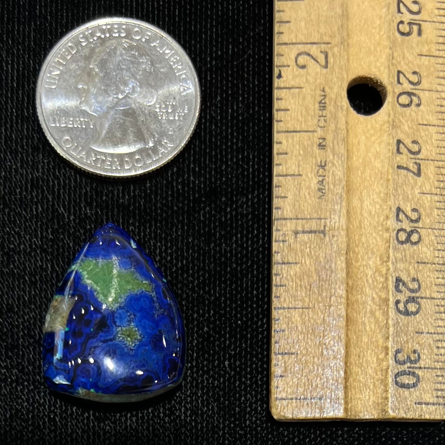 A loose pear shape cabochon cut blue azurite stone with green pseudomalachite inclusions.