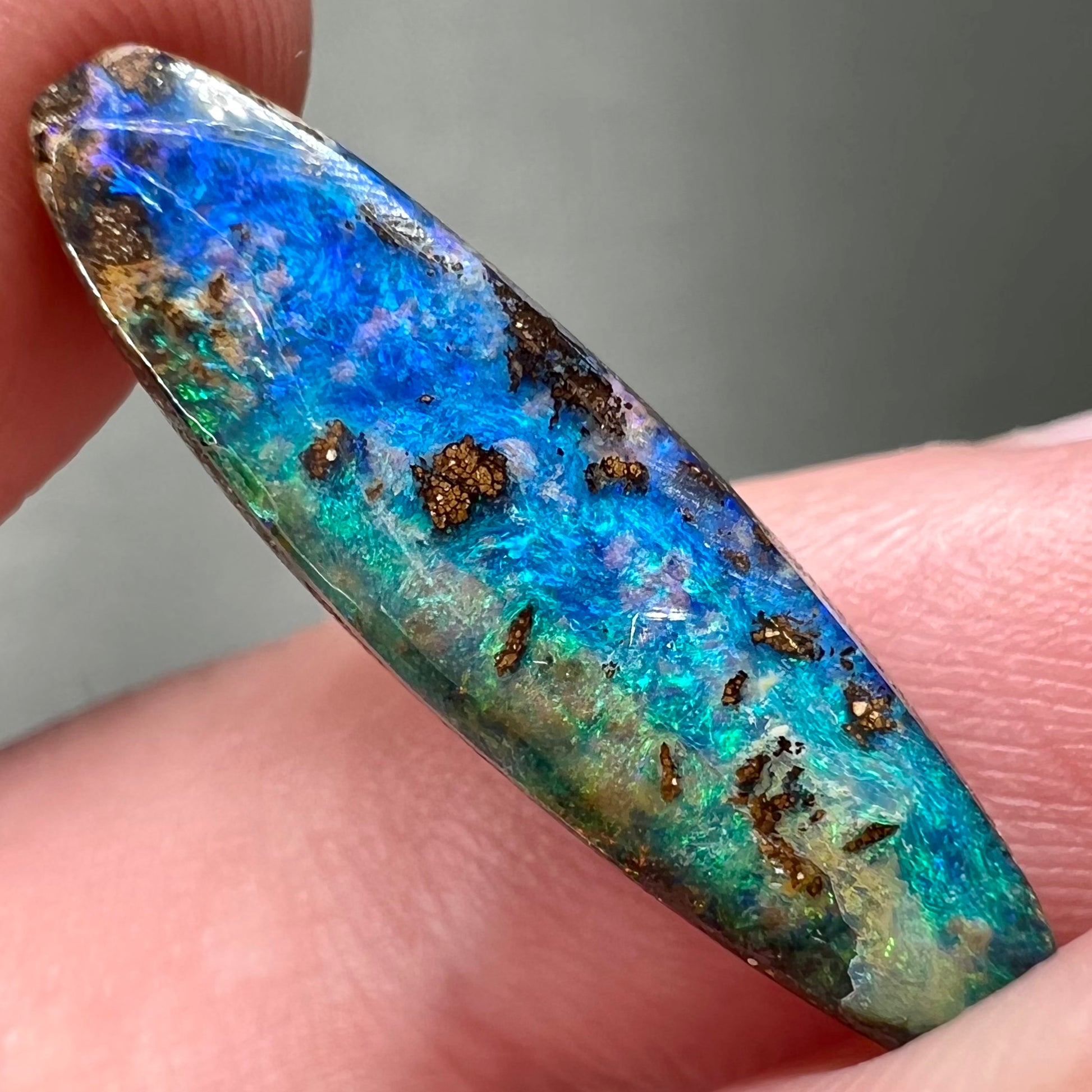 A loose, oval cabochon cut Australian boulder opal from Quilpie, Australia.  Predominant colors are blue and green.