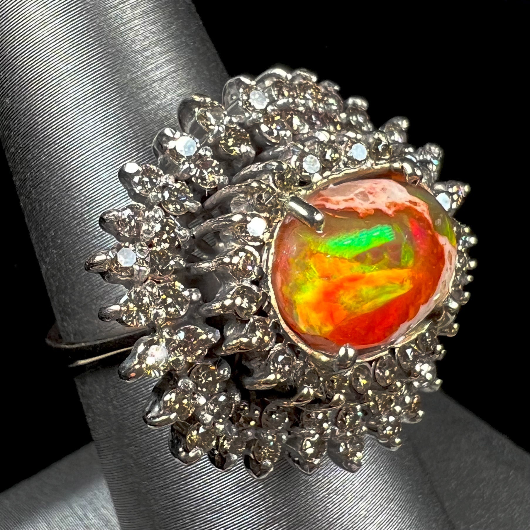 An 18k white gold orange fire opal ring set with a triple halo of diamonds.