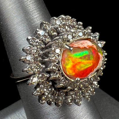 An 18k white gold orange fire opal ring set with a triple halo of diamonds.