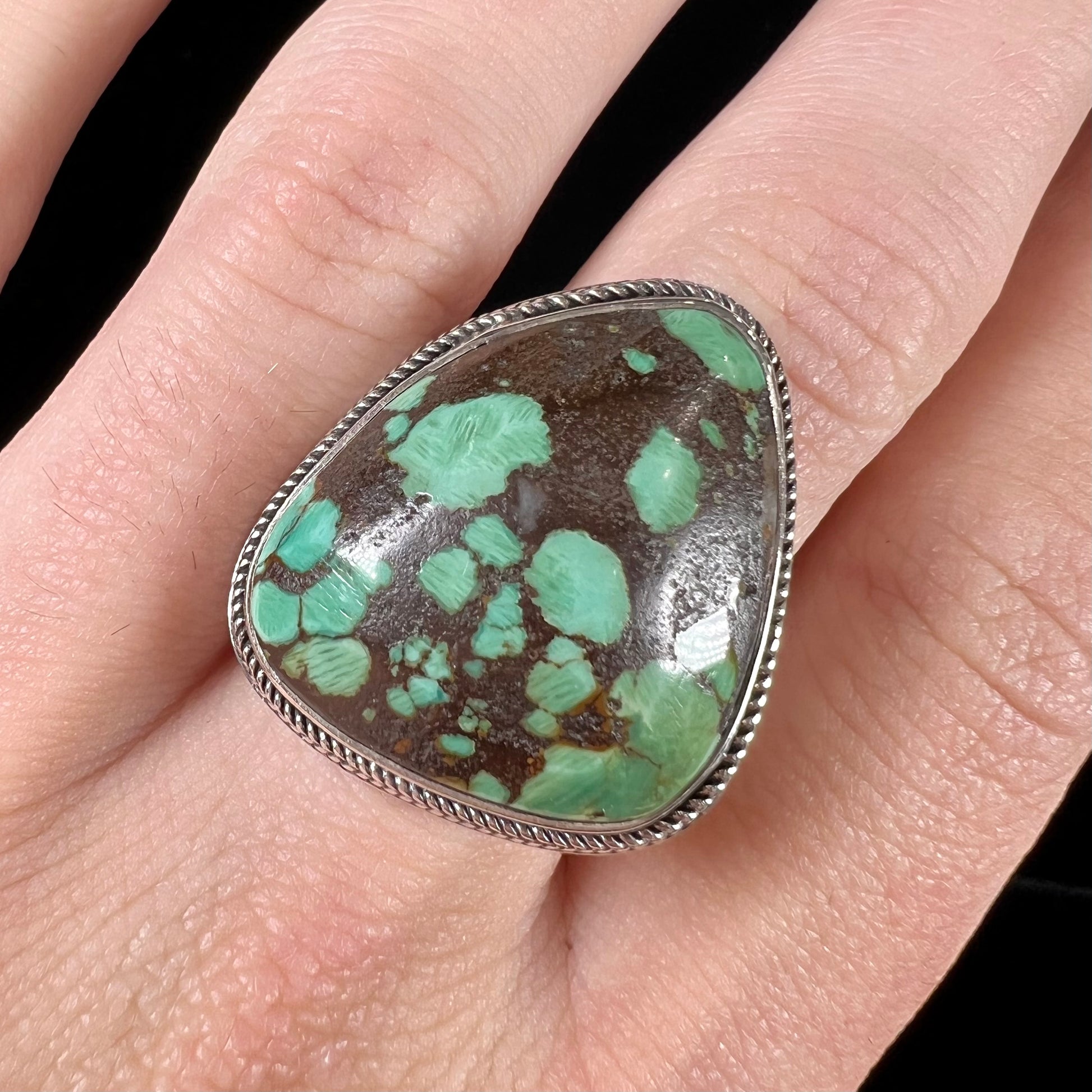 A sterling silver ring bezel set with a green spotted turquoise stone from Carico Lake, Nevada.